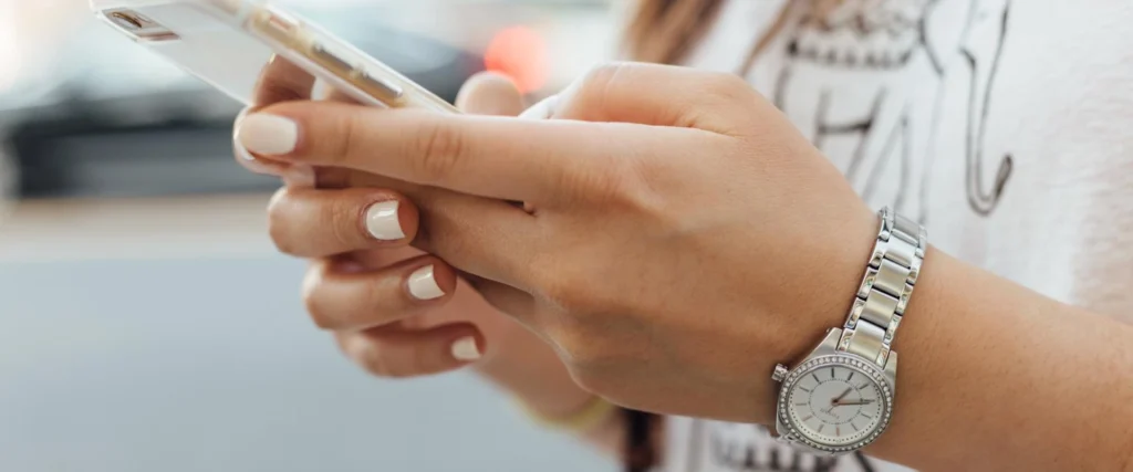 Nell'immagine si vedono le mani di una ragazza che reggono uno smartphone e le sue dita digitano sullo schermo